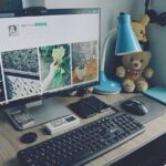 A tidy home office desk setup with a computer, keyboard, and personal items, creating a cozy work atmosphere.