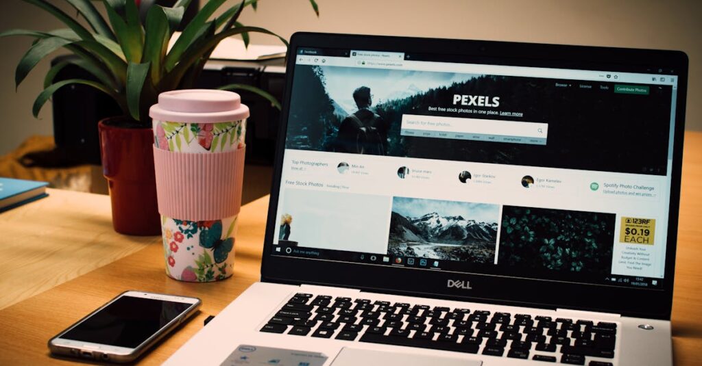 A tidy desk setting with a laptop showing a stock photo website and a smartphone.